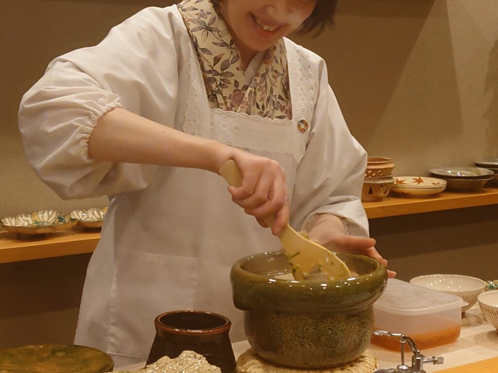 千葉市の日本料理みつはしの鯛と松茸の土鍋ご飯をかき混ぜている女将